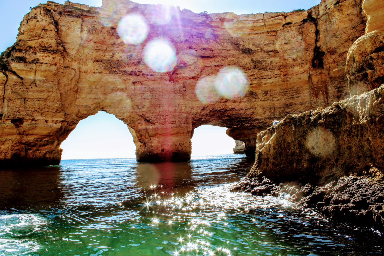 Sea caves in the Algarve with sun glinting on turquoise water